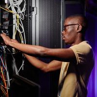 Side view portrait of adult African American man repairing server and setting up data network